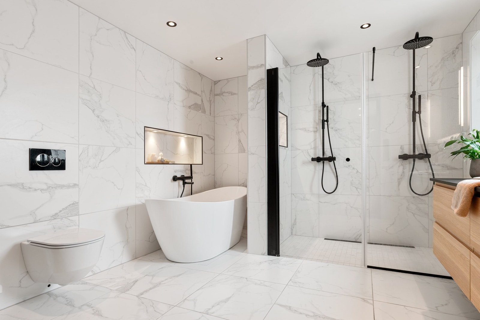 Superlekkert bad/wc med 2 dusjer, frittstående badekar, store lekre fliser og veggehengt toalett. Spotter i tak og lekker innfelt hylle i vegg ved badekar. Galleribilde