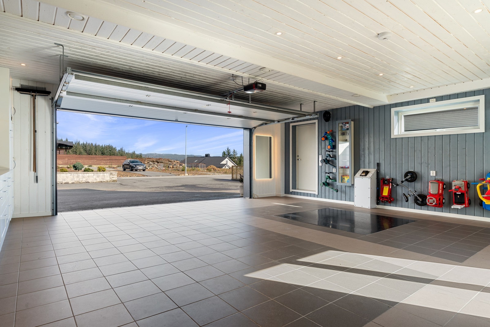 Nydelig garasje med dør til parkeringsplass og til hage. Fliser på gulv. Innfelt egen saksebukk. Spotter i tak. Galleribilde