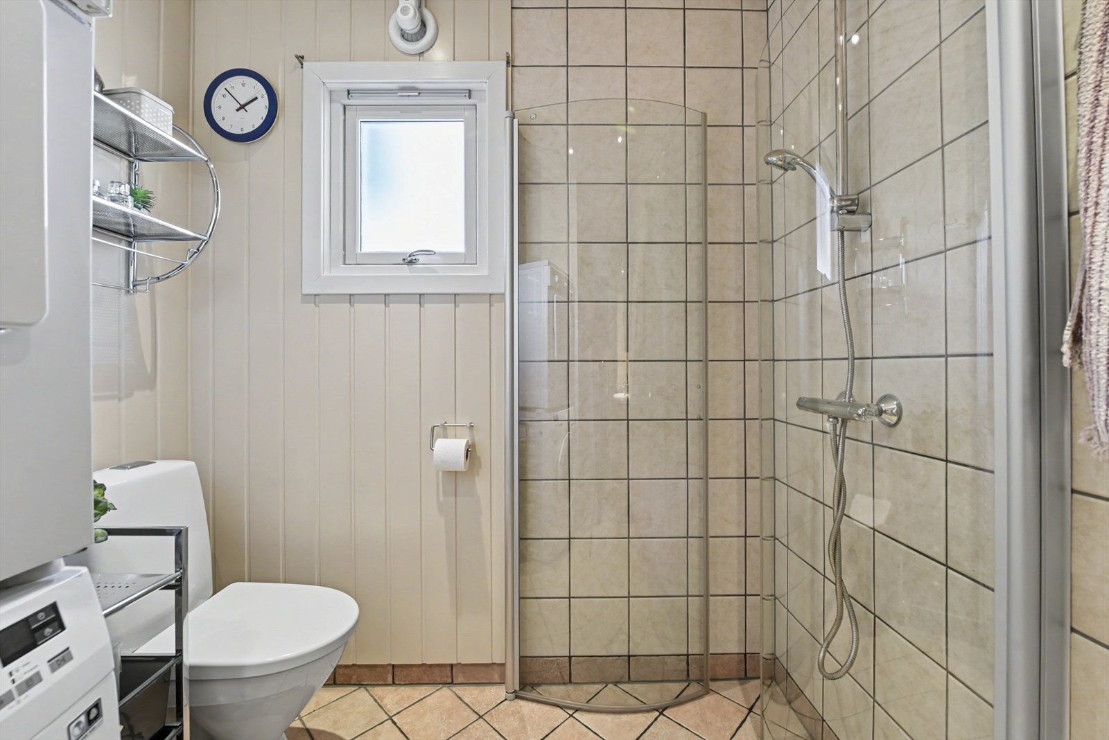 Rommet har en praktisk dusjnisje med glassdører og opplegg for vaskemaskin. Toalettet er fra 2023. Galleribilde