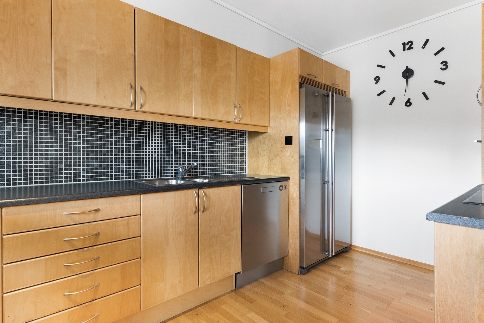 Kjøkkenet har rikelig med skap og benkeplass, mosaikkflis over benkeplate gir et moderne uttrykk. Galleribilde