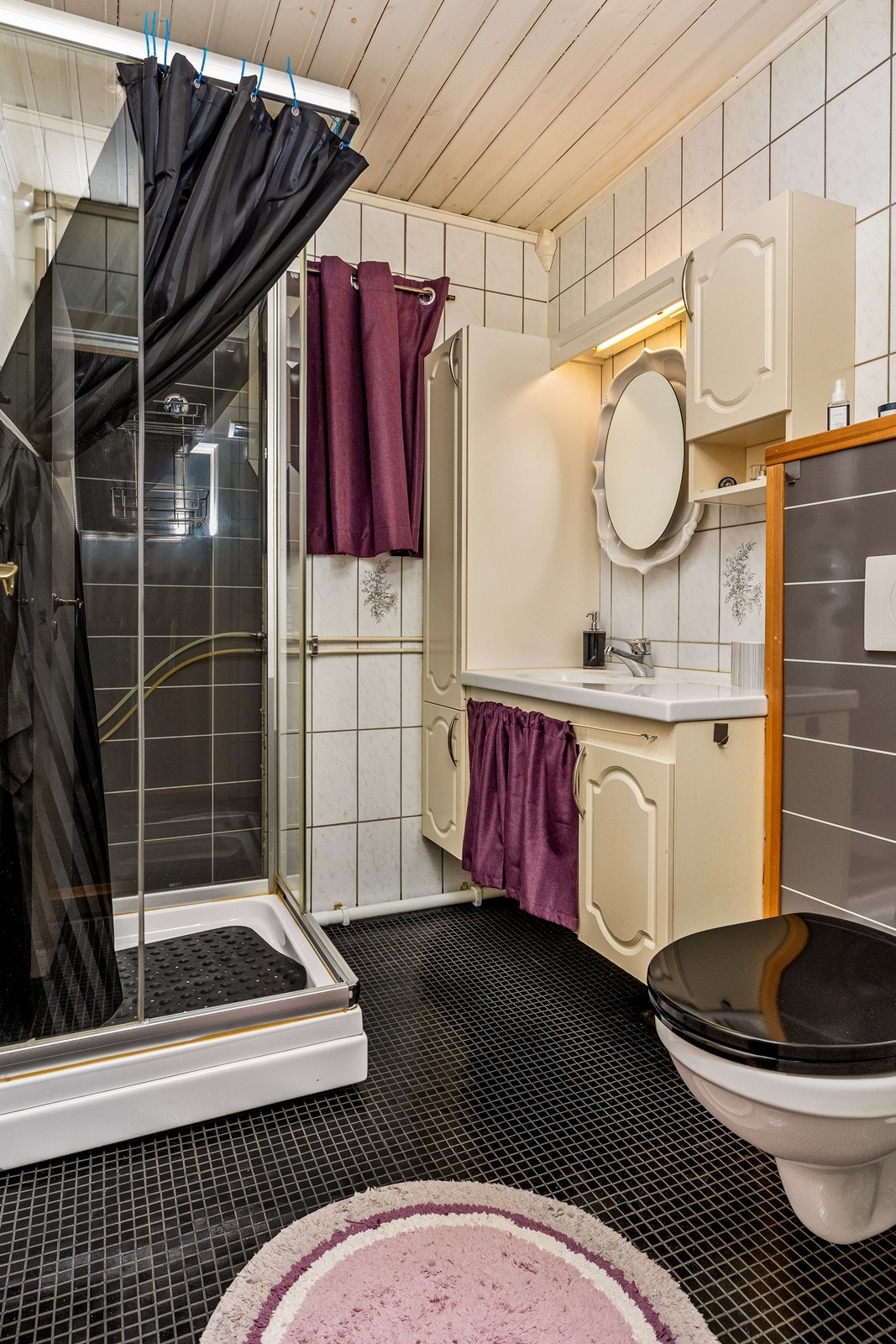 Badet er flislagt og innredet med dusjkabinett, servant og innebygget toalett. Galleribilde