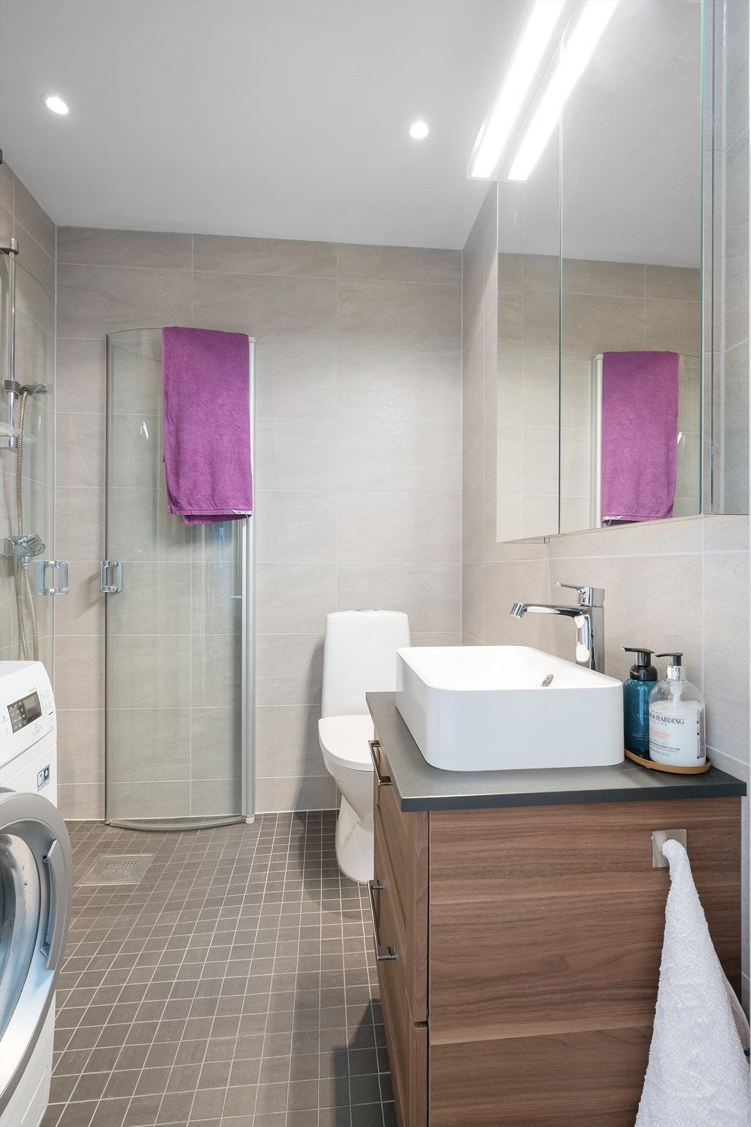 Badet er helfliset og er utstyrt med Ikea innredning, speilskap med dobbelsidig speil, tilkoblingsmulighet for vaskemaskin (40cm), fordelerskap, (tilknyttet bad og kjøkken), hjørnedusj med buet, innfellbare glassvegger, sluk i gulv og avtrekksvifte Galleribilde