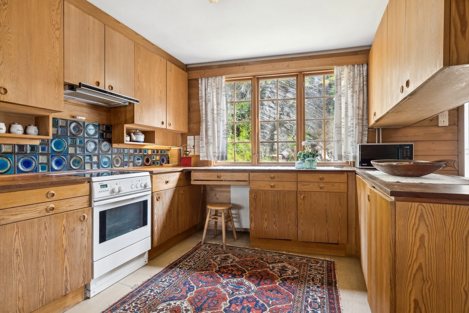 Et godt arbeidskjøkken. Flotte keramiske fliser over benk designet av anerkjente kunstner Konrad Galaaen. Galleribilde