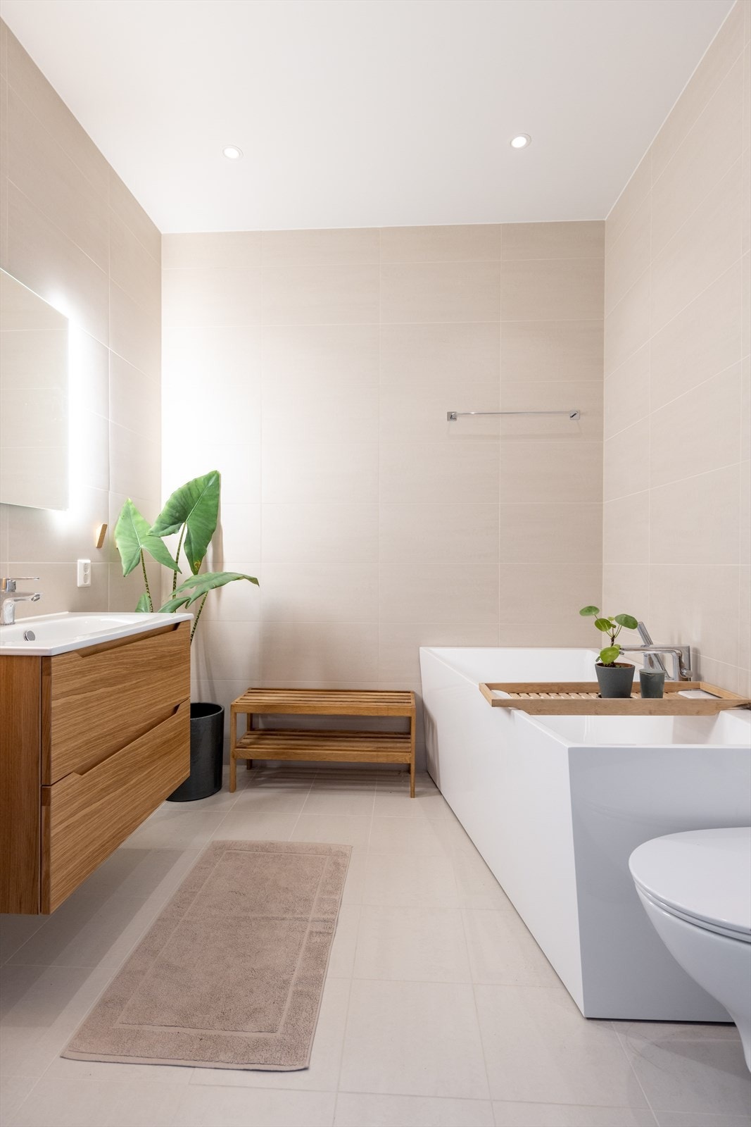 Badet i 2. etasje er helfliset med varmekabler i gulvet, og på dette badet er det valgt badekar i moderne design. Badet med et dust og innbydende fargevalg har innredning med heldekkende servant og speil med integrert belysning. Vegghengt toalett. Galleribilde