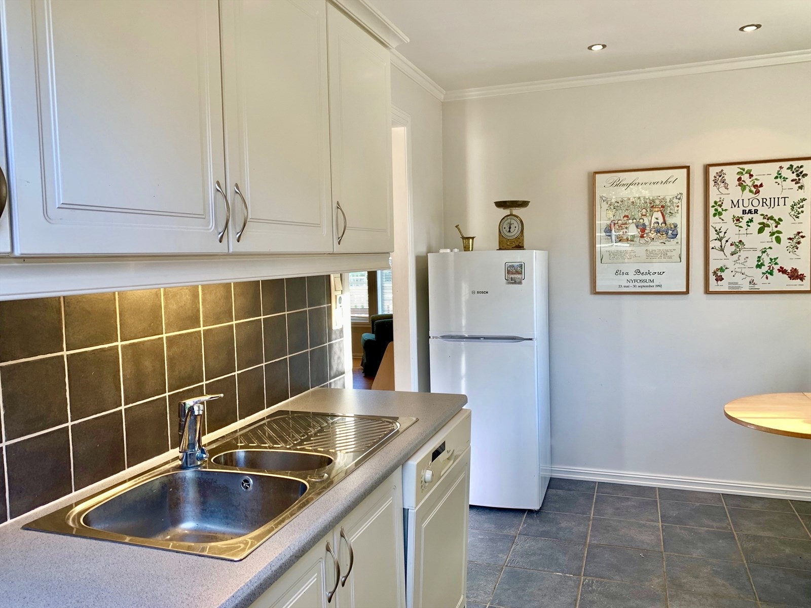 Kjøkkeninnredningen er fra 2003 og levert av Sigdal Kjøkken AS. Innredningen har hvite, profilierte fronter og laminert benkeplate med nedfelt utslagsvask. Galleribilde