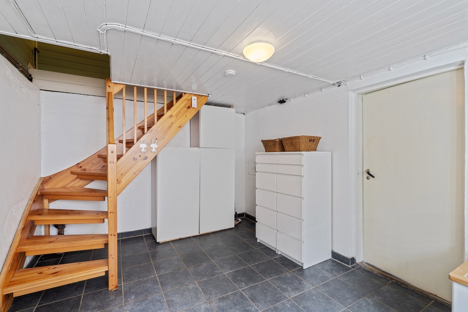Trapperommet i kjelleren har lakkert tretrapp og god plass til oppbevaringsmøbler. Galleribilde