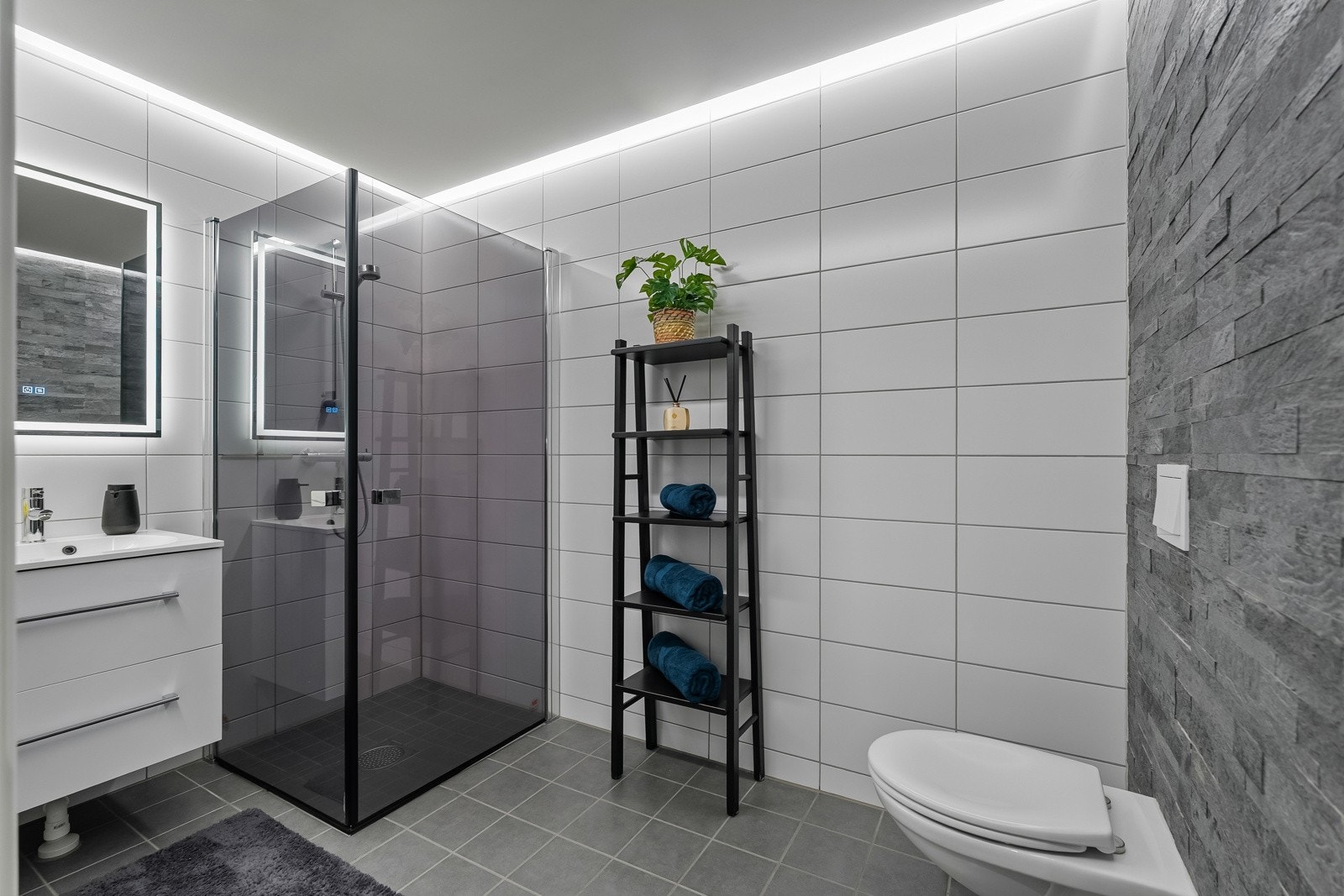 bade i undertetasjen har moderne innredning med skuffer, glatte fronter, veggfestet klosett med innebygget sisterne, servant og dusj med herdet glassdører. Galleribilde