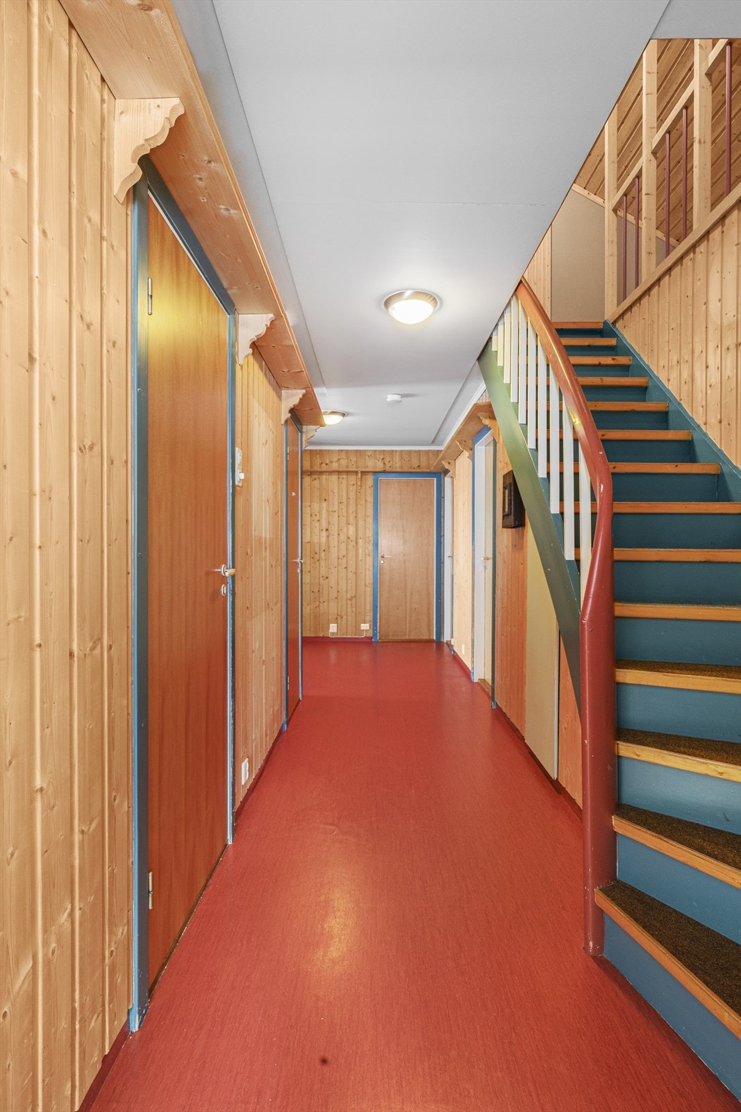 Trappen til loftet har teppebelegg, mens gangen har panelkledde vegger og rødt gulvbelegg. Galleribilde