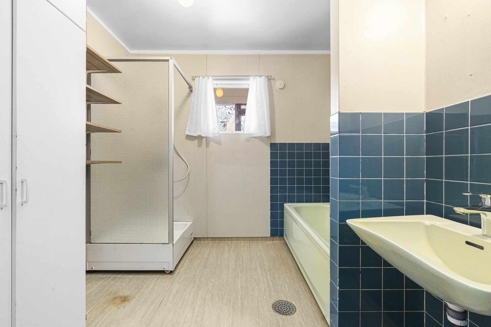 Badet har gulvbelegg, tapet og keramiske fliser på vegger, naturlig ventilasjon og stråleovn over døren. Galleribilde