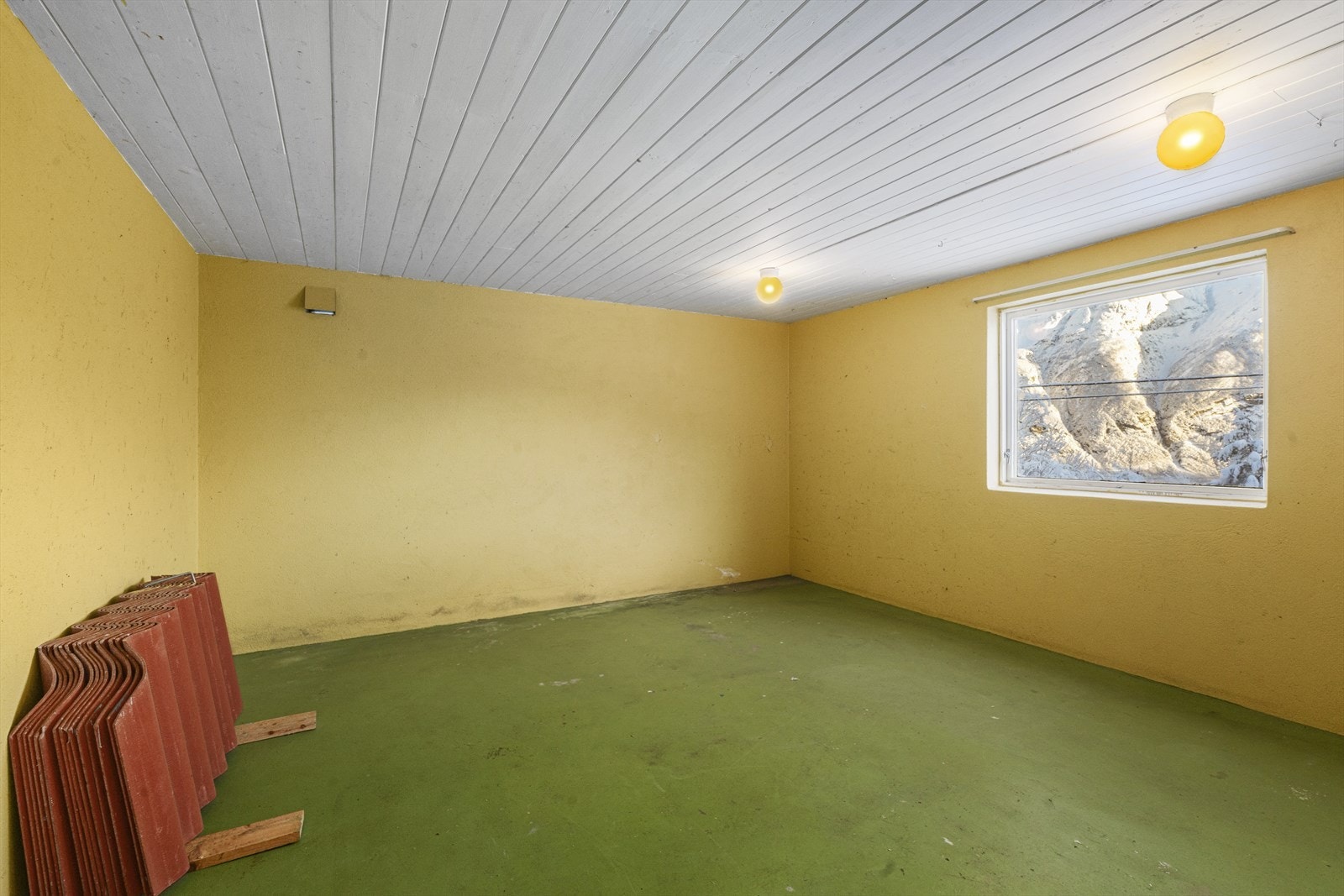 Hobbyrom i kjeller har malt murvegger og et stort vindu som gir naturlig lys. Galleribilde