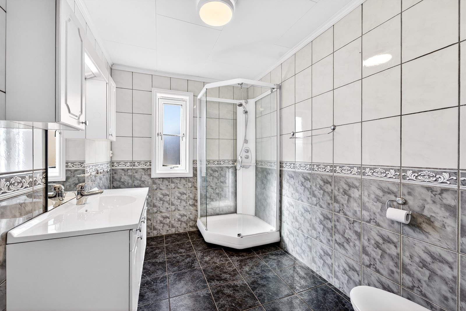 Fliselagt bade med varmekabler i gulv. Innredet med baderomsinnredning, toalett og dusjkabinett. Galleribilde