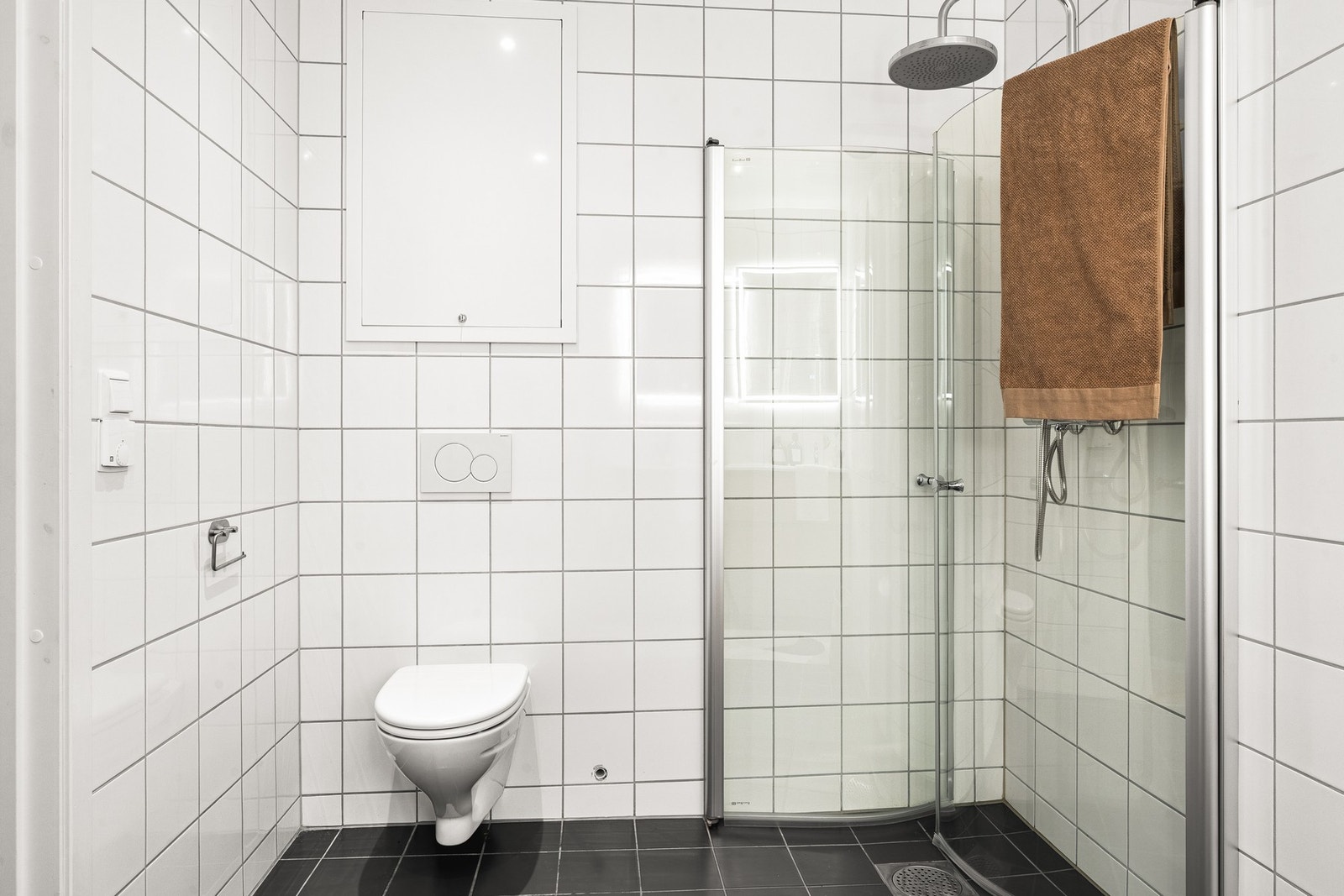 Badet er innredet med vegghengt toalett, servant med innredning, dusjhjørne og opplegg for vaskemaskin. Galleribilde