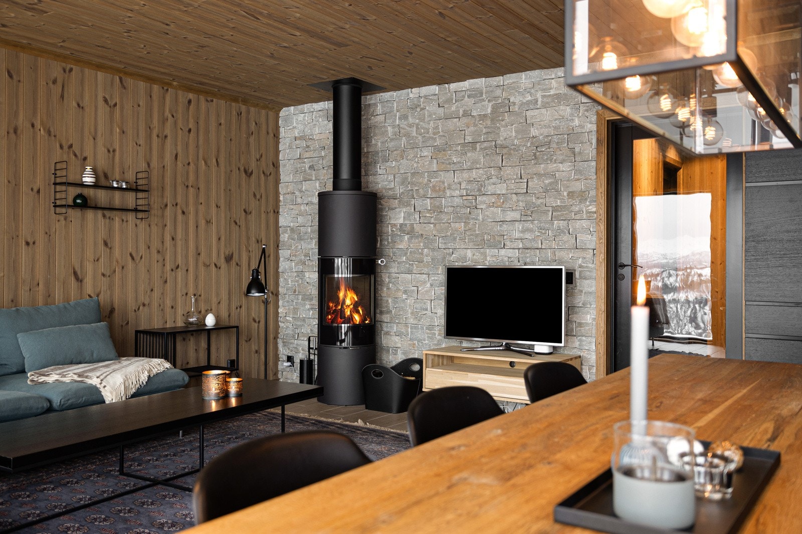 Stue/kjøkken, hvor man fra begge soner kan nyte synet av flammene som flakker i peisen Galleribilde