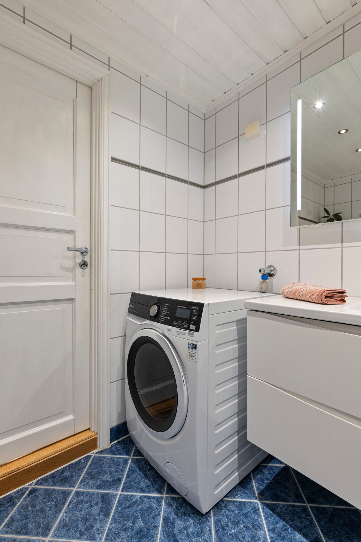 Badet er utstyrt med servant, veggfestet klosett, badekar og opplegg til vaskemaskin Galleribilde