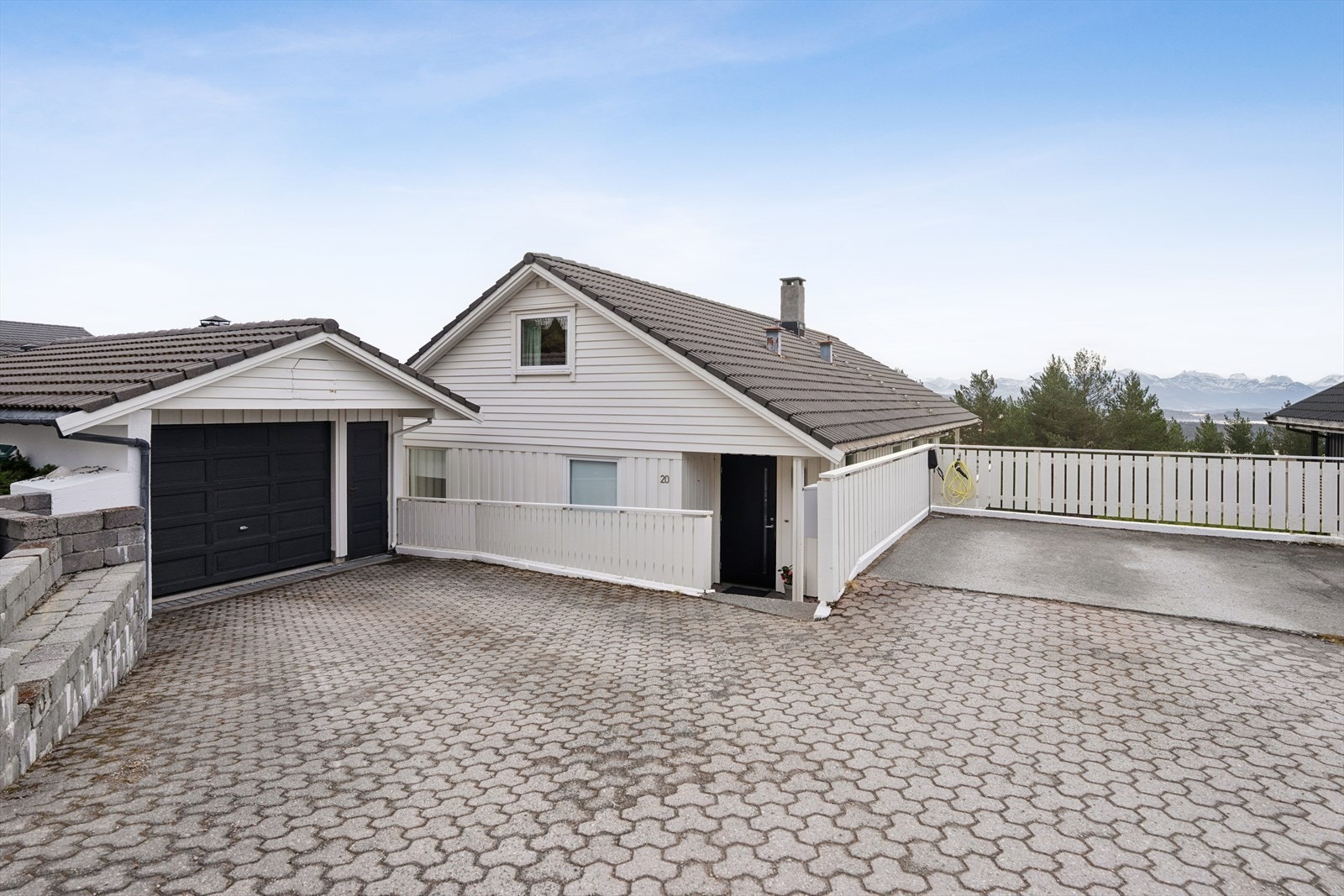 Eiendommen har en pent steinbelagt gårdsplass med rikelig med biloppstillingsplass, garasje og elbillader. Galleribilde