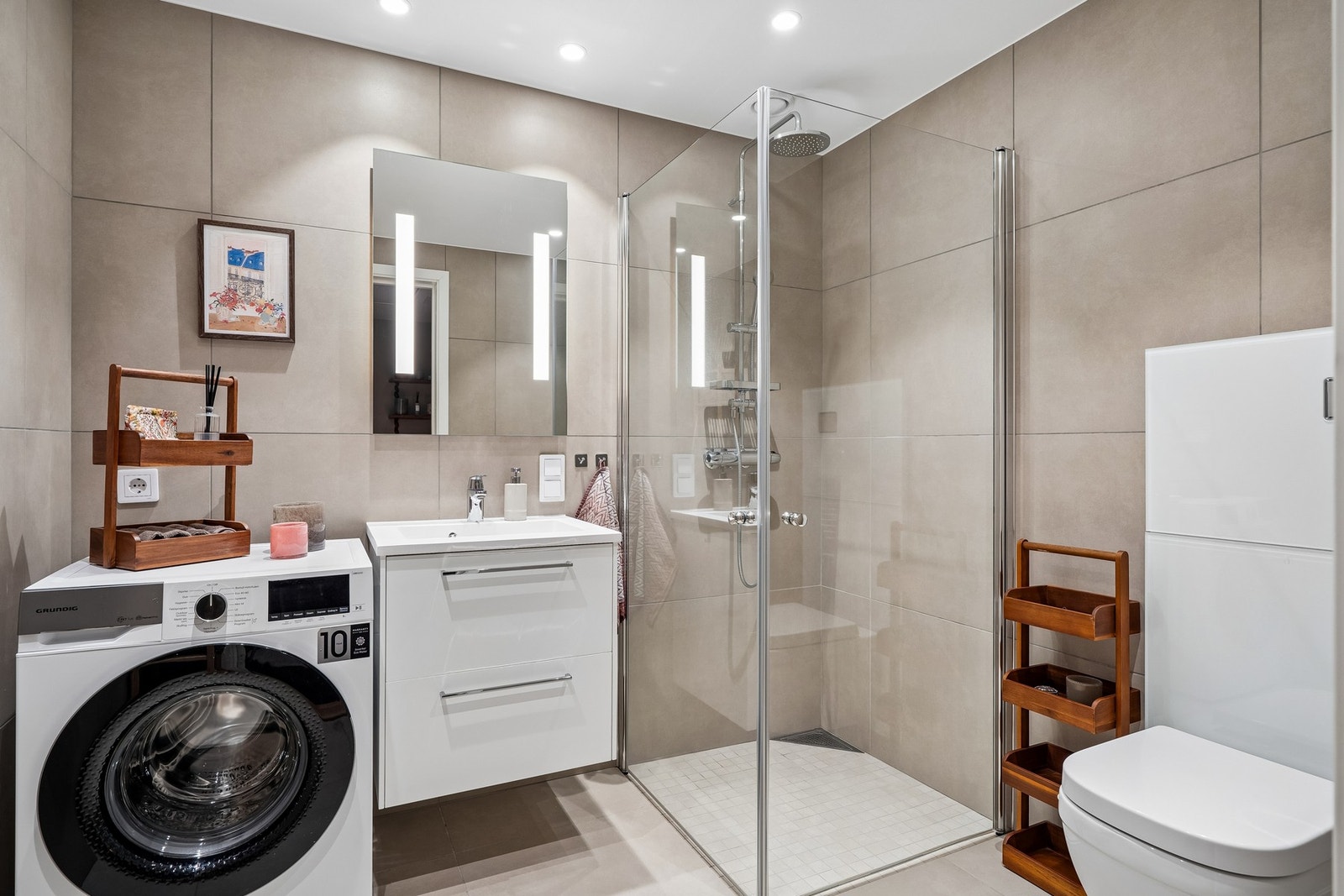 Flislagt bad med vegghengt toalett og opplegg for vaskemaskin. Galleribilde