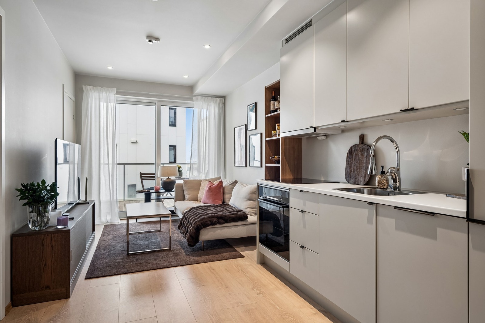 Lys og moderne oppholdsrom med åpen kjøkkenløsning og hyggelig sone for både matlaging og avslapning. Galleribilde