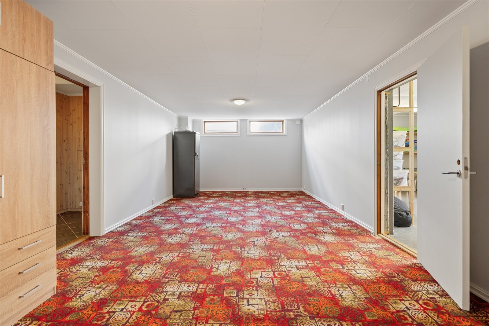 Kjellerstue med teppebelagt gulv. Her er det fremlagt rør for enkel tilkobling av radiator med vannbåren varme. Galleribilde