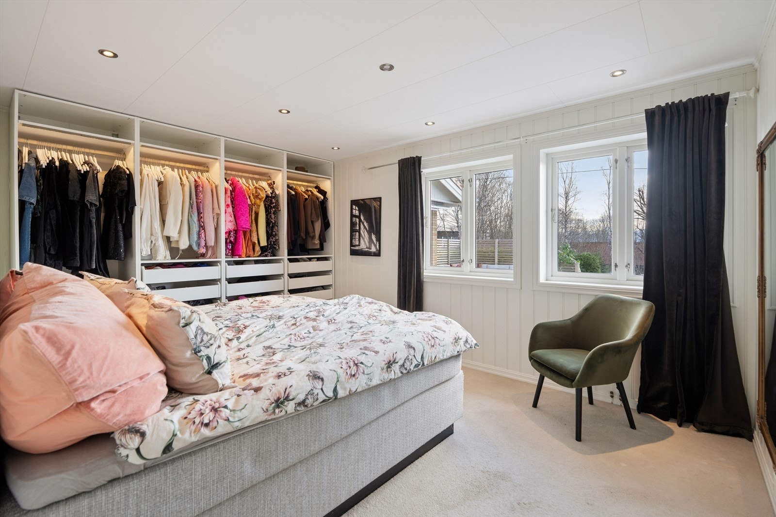 Ett av soverommene i første etasje, med teppegulv for komfort og en stor, åpen garderobeløsning. Galleribilde