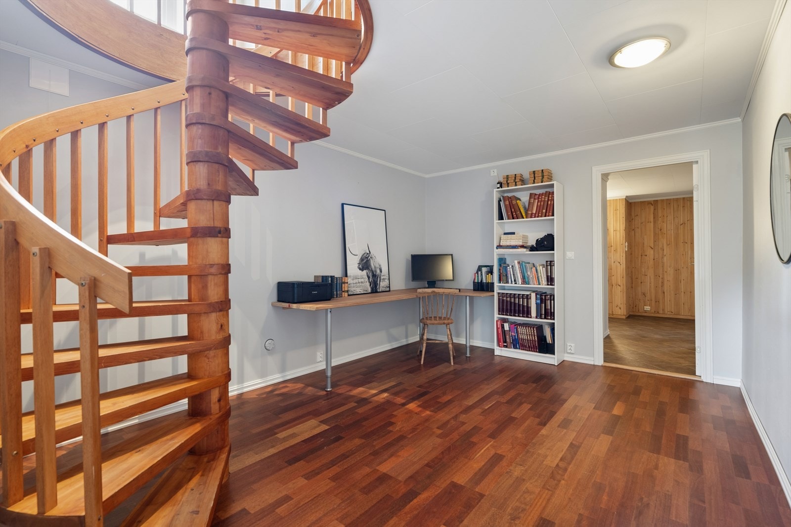 En lakkert spiraltrapp i tre forbinder de to etasjene. Gangen i kjelleren har parkettgulv. Galleribilde