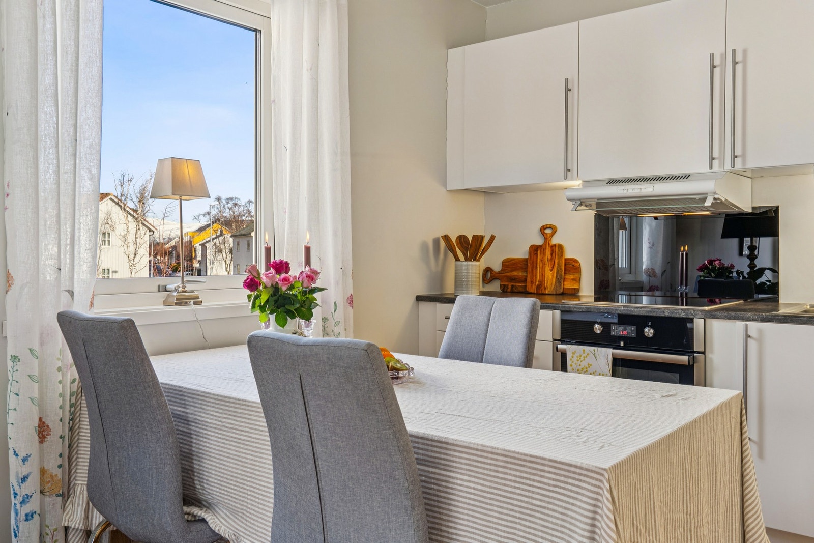 Kjøkkenet har en hvit, slett innredning og en praktisk spiseplass ved vinduet. Galleribilde