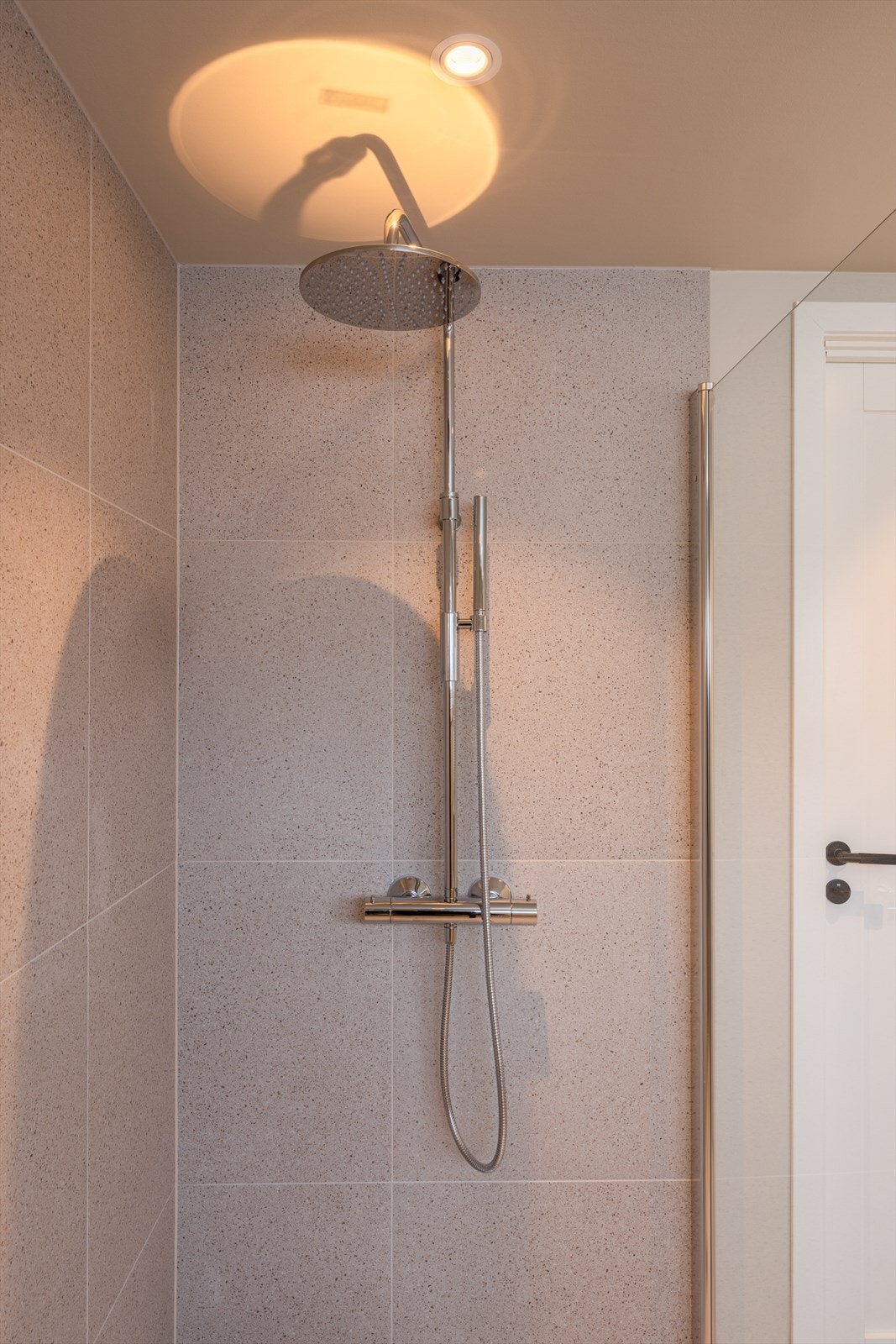 Dusjhjørnet er helfliset med regnfallsdusj, hånddusj og innfellbare glassdører. Galleribilde