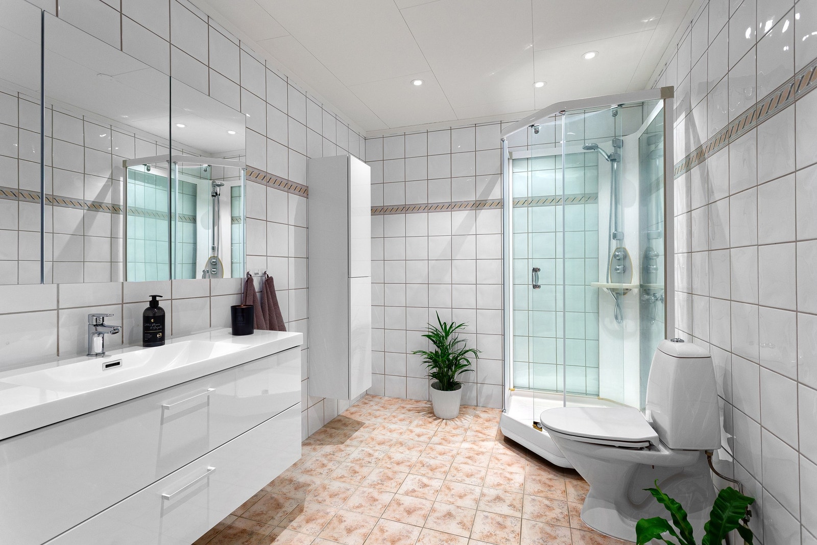 Flislagt bad med gulvvarme. Downlights i himlingen. Innredet med vegghengt servantskap med skuffer. Speilskap på vegg over servant. Galleribilde