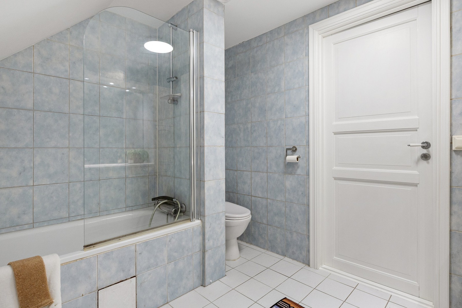 Badekar med vegghengt badekararmatur. Gulvstående toalett og mekanisk avtrekksvifte i himling. Galleribilde