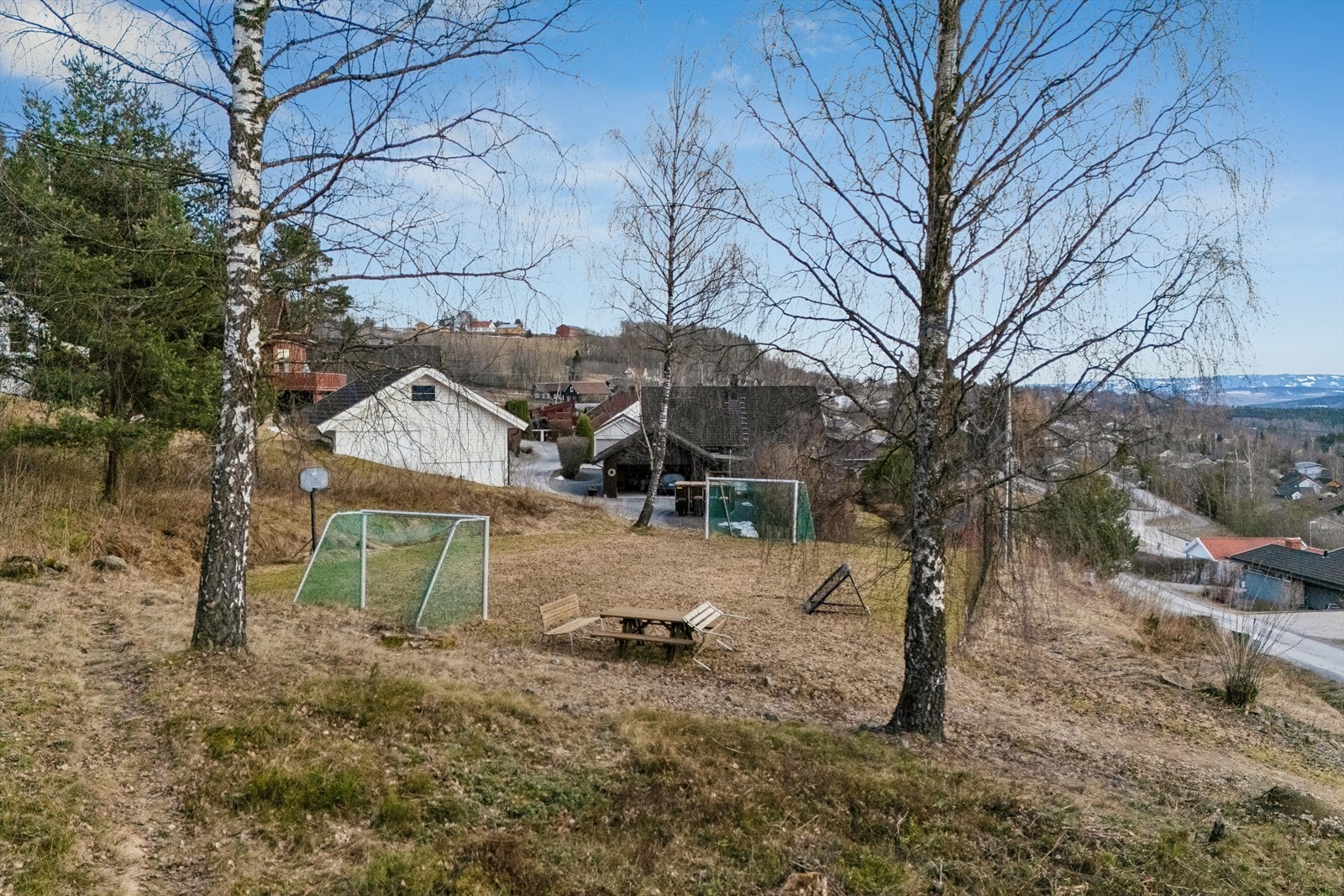 Tomten ligger i et svakt skrånende terreng og er opparbeidet med plen, busker og trær. Galleribilde