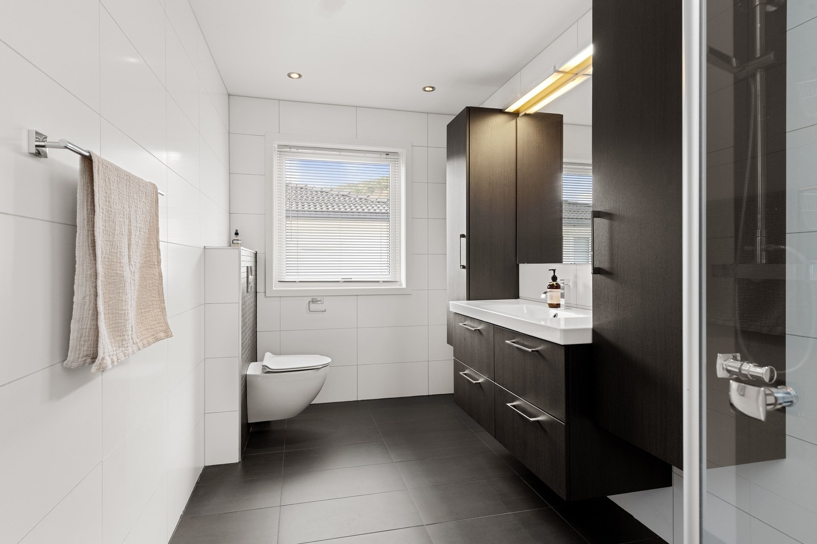 Flislagt bad med varme i gulvet, vegghengt toalett og downlights i taket. Galleribilde