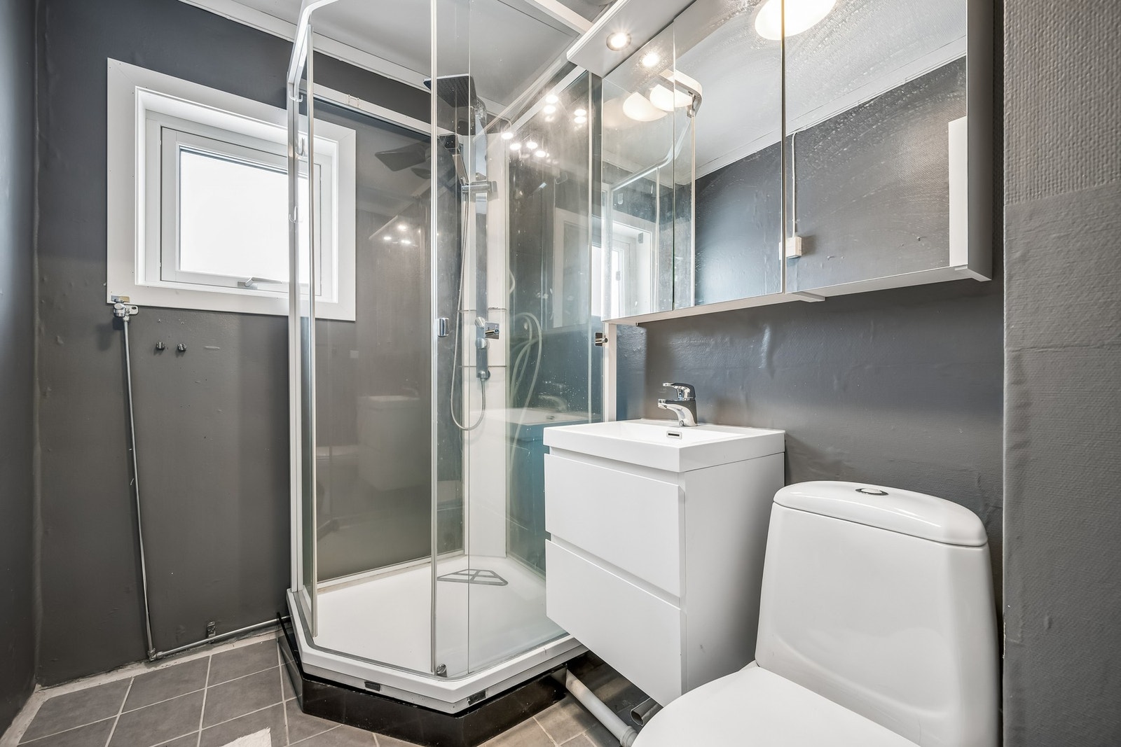 Rommet er innredet med en baderomsinnredning med servant fra 2024, et toalett og et praktisk dusjkabinett. Det er muligheter for å ha vaskemaskin og tørketrommel på badet. Galleribilde