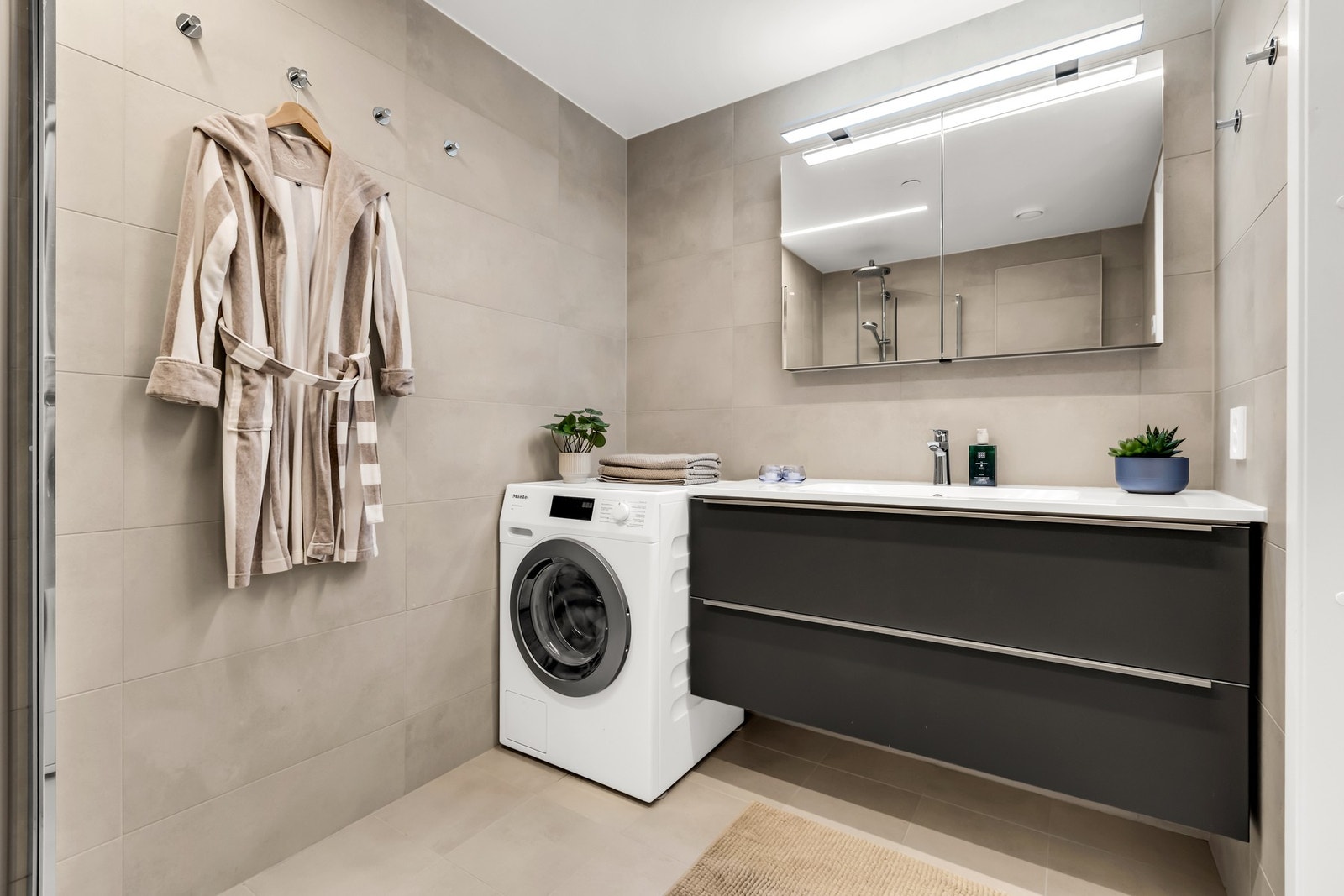 Baderommet har dusjløsning med glassvegger og vegghengt toalett Galleribilde