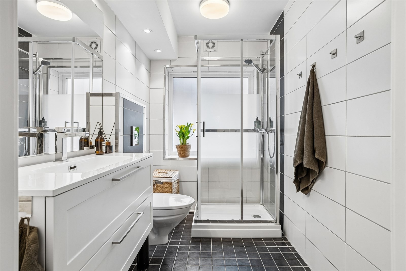 Badet er helfliset og utstyrt med varme i gulvet, servant med innredning, vegghengt toalett og dusjkabinett. Galleribilde