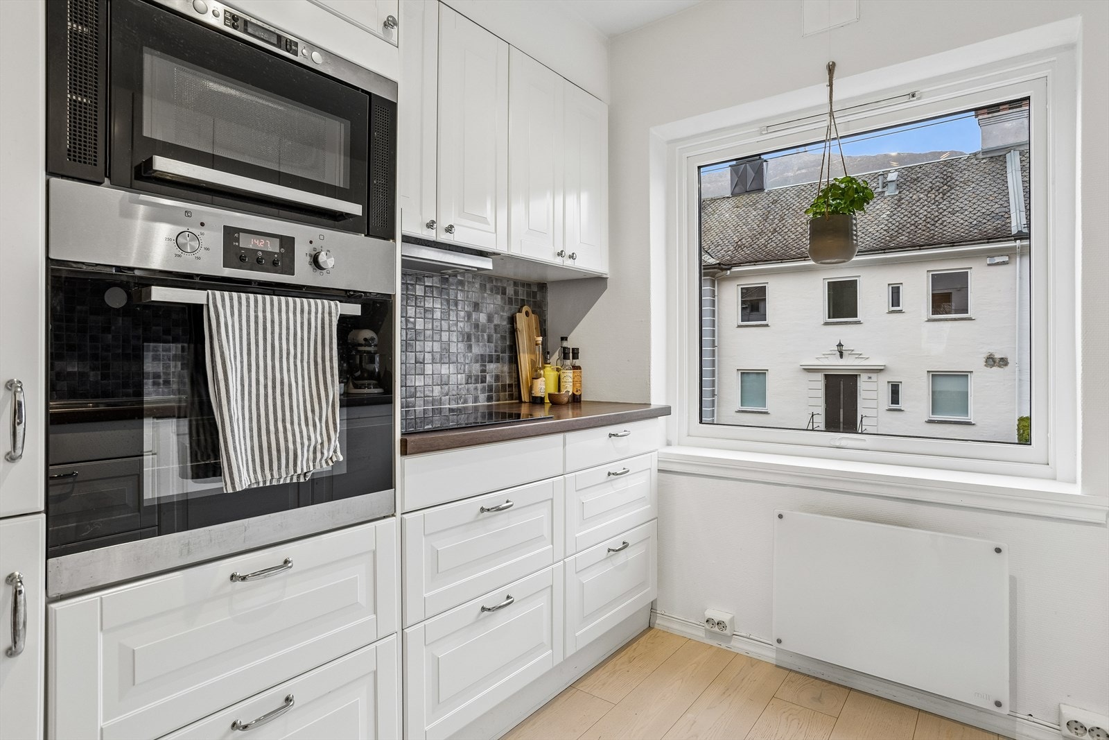 Kjøkkeninnredningen har profilerte fronter og mosaikkfliser over en laminert benkeplate. Galleribilde