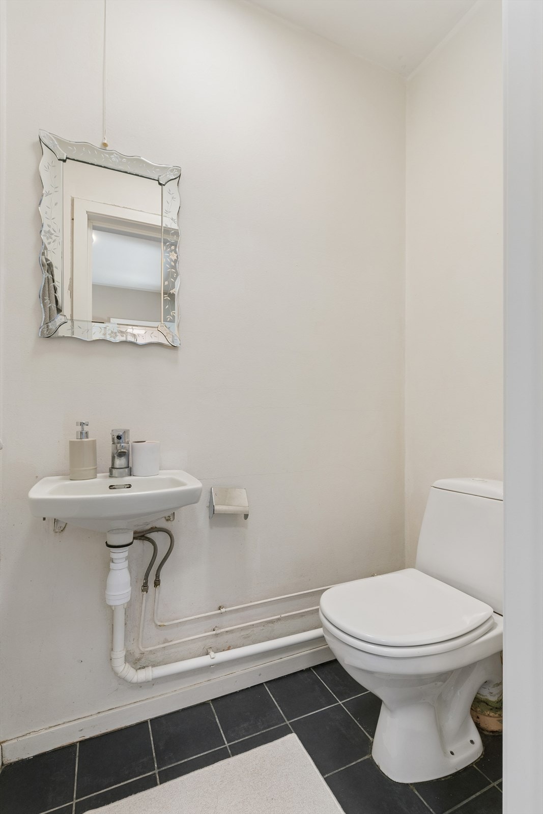 Separat wc med fliser på gulv og malte veggoverflater, innredet med servant i helstøpt plate og klosett Galleribilde