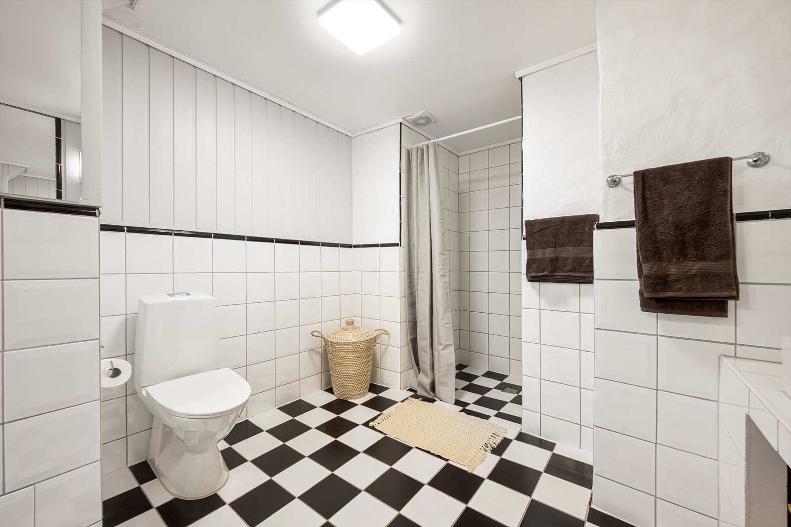 Stort, funksjonelt bad med flislagt gulv med behagelig varme og veggene har en kombinasjon av fliser, mur og panel. Galleribilde