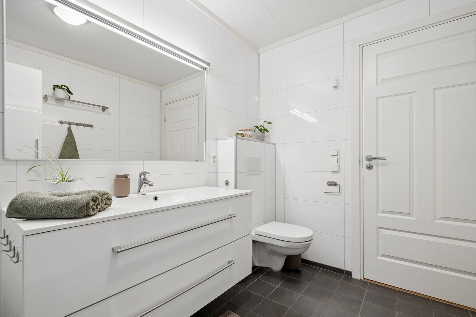 Innredet med vegghengt toalett, badekar/dusj, vask og baderomsinnredning. Galleribilde