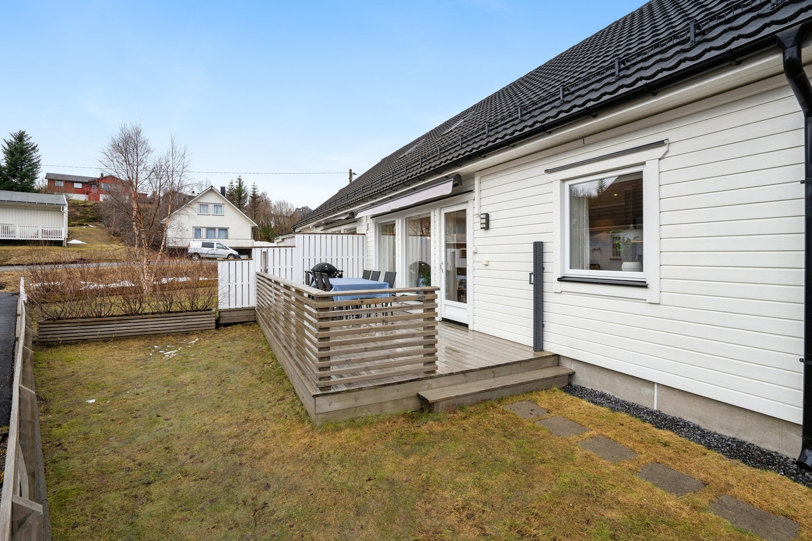 Pent opparbeidet uteområdet foran boligen med noe plen, gjerde og terrasse. Galleribilde