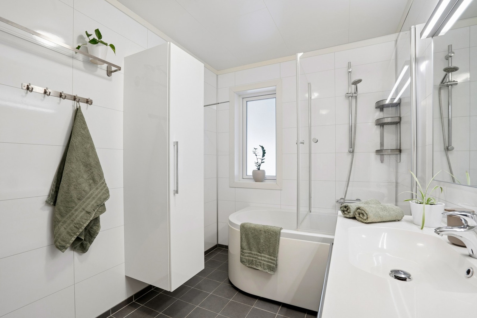 Bad med lyse våtromsplater på vegger og mørke fliser på gulvet. Galleribilde