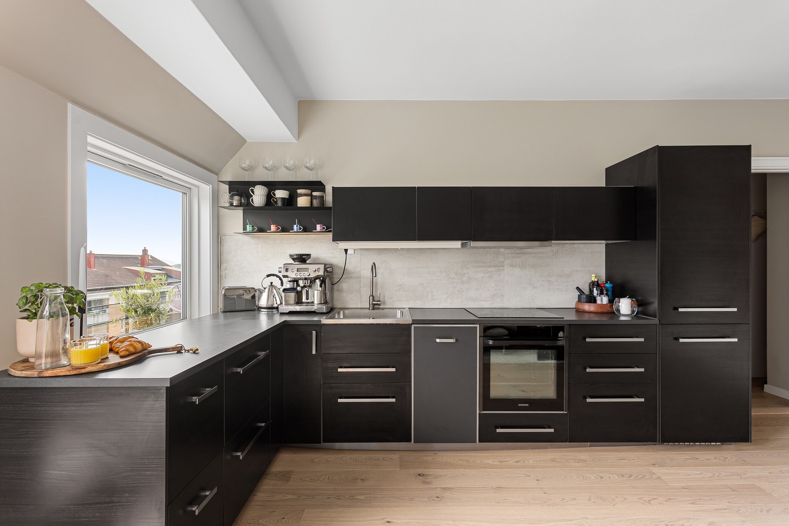 Moderne kjøkkeninnredning fra 2016 med god skap- og benkeplass. Innredningen har mørke glatte fronter og laminert benkeplate med nedfelt oppvaskkum. Praktisk med plater i benkeryggen og belysning under overskapene. Galleribilde