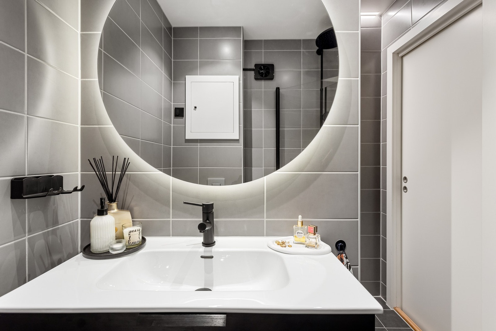 Moderne baderomsinnredning med skuffer og heldekkende servant, rundt speil med integrert belysning over. Galleribilde