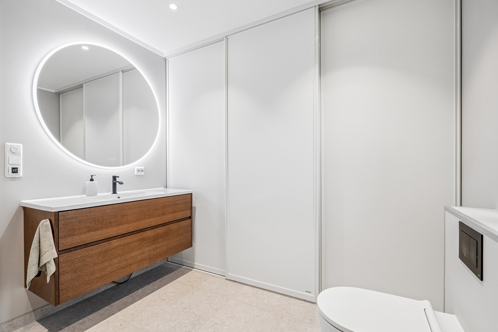 Spotter i taket og speil med belysning, samt skyvedørsgarderobe som skjermer opplegg for vaskemaskin. Galleribilde