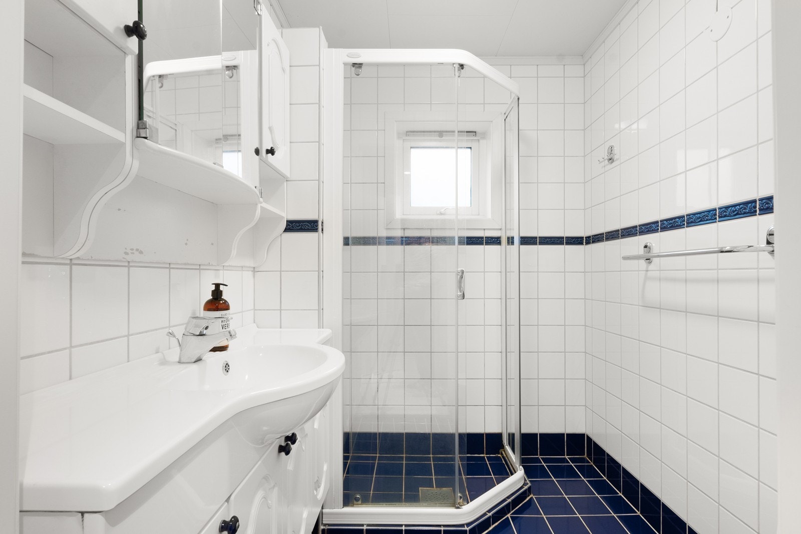 Badet har praktisk adkomst fra entréen, og flislagte overflater på vegger og gulv. Galleribilde