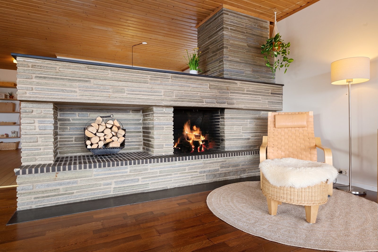 Peisområdet er et markant og stilfullt blikkfang i stuen, med en bred peisvegg utført i naturstein som tilfører rommet både karakter og tyngde. Galleribilde