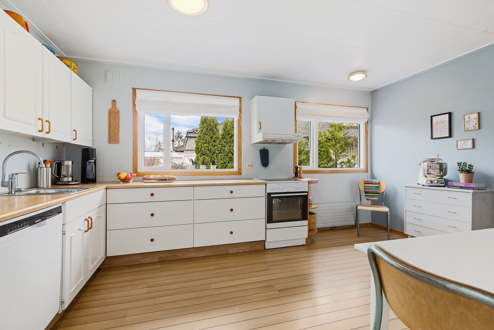 Kjøkkenet har en pen og tidløs innredning fra 1973 med hvite, glatte og profilerte fronter, samt laminert benkeplate med nedfelt kjøkkenkum. Galleribilde