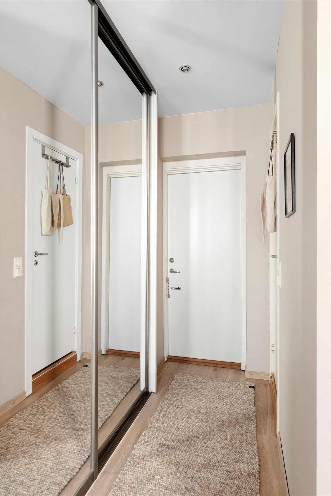 Leiligheten har en innbydende entré som gir et svært godt førsteinntrykk. Her er det gode oppbevaringsmuligheter for yttertøy og sko i en romslig skyvedørsgarderobe med speilfronter, som også bidrar til en lysere og mer romslig romfølelse. Galleribilde