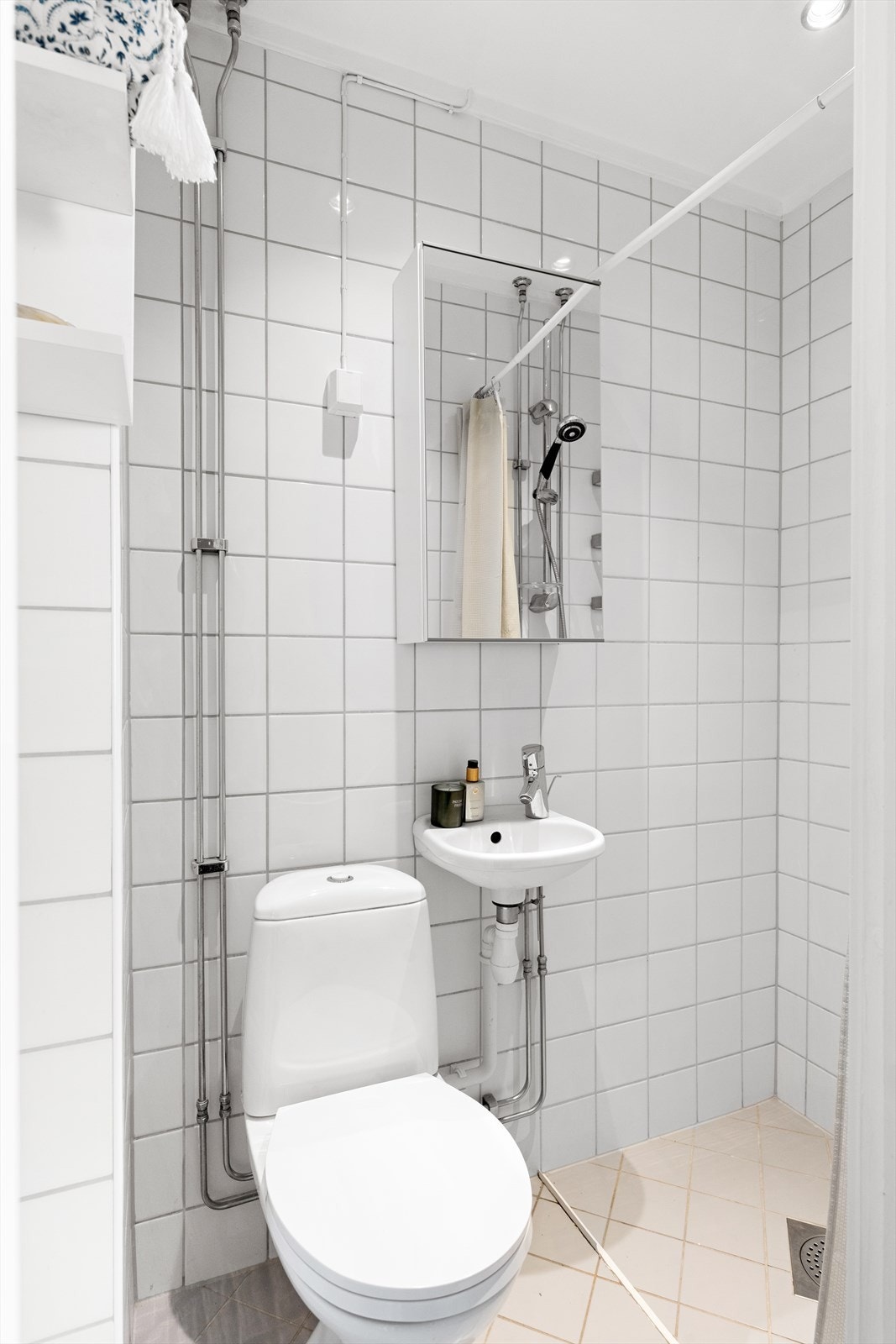 Badet er funksjonelt innredet med gulvstående toalett, dusjhjørne samt servant med speil og belysning. Galleribilde