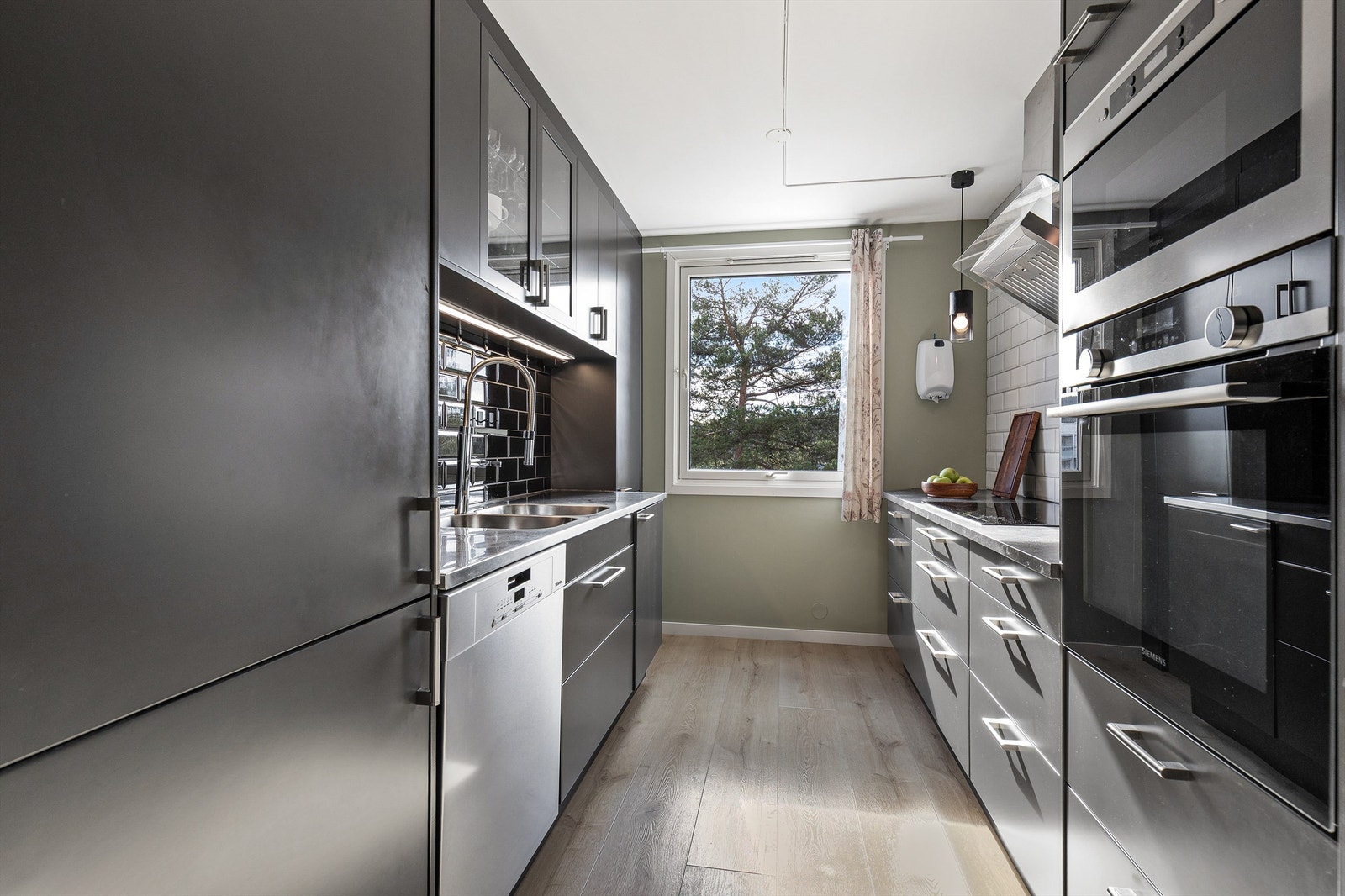 Et funksjonelt og velutstyrt kjøkken, utstyrt med integrert kjøl- og fryseskap, stekeovn og mikrobølgeovn. Galleribilde