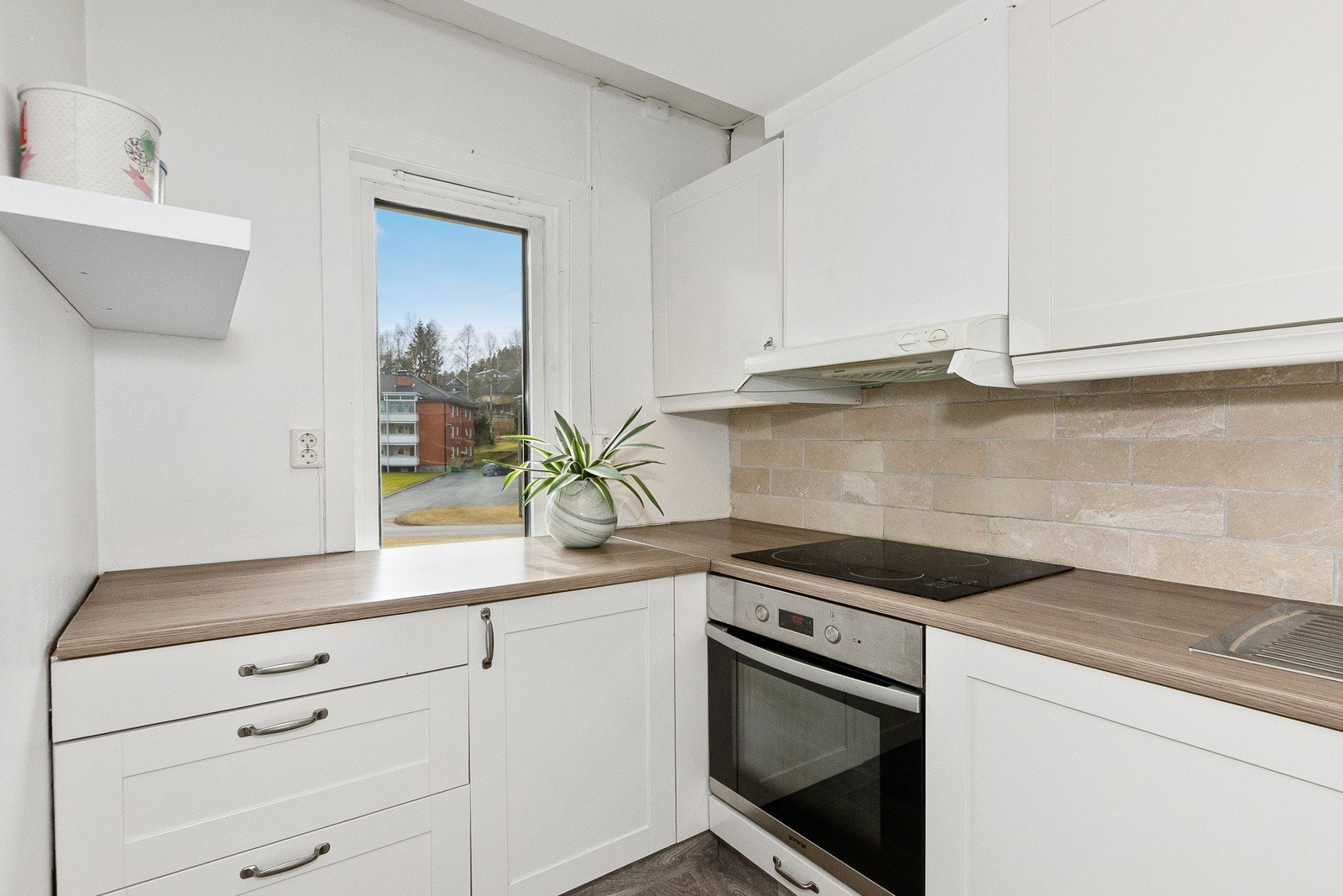 Hvit profilert kjøkkeninnredning med fliser over benk Galleribilde