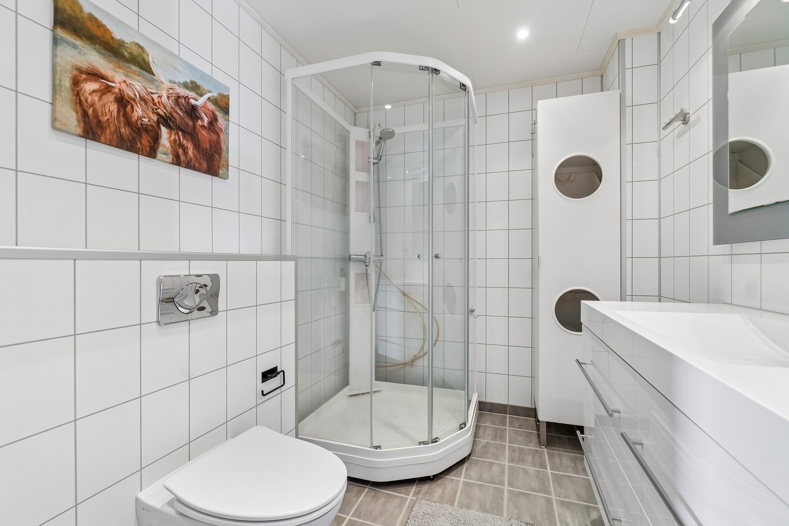 Av inventar finner du vegghengt toalett, et stort dusjkabinett, en stilren baderomsinnredning med innfelt servant, innfelte spotter i himling, og et stort speil. Galleribilde